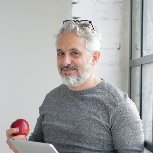 A bearded man with white hair looking into the camera