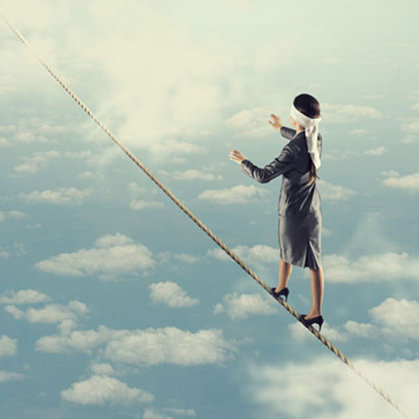 blindfolded women with arms stretched out in front of her, wearing a suit, stepping onto a high wire in the sky surrounded by clouds