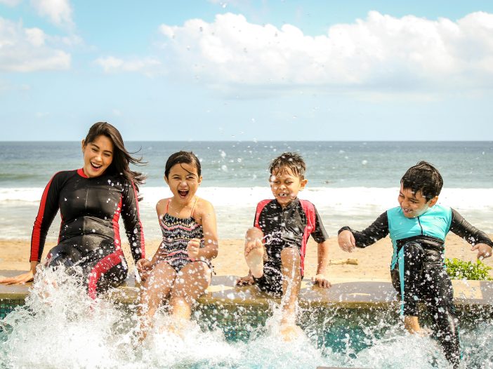 Family at the beach spending time together surfing with the kids