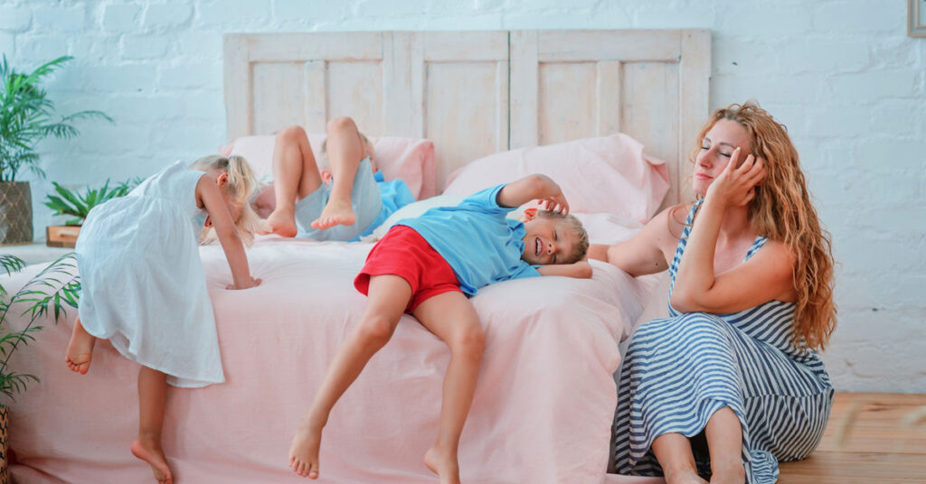 tired mum with children at the end of the day, sprawled on the bed