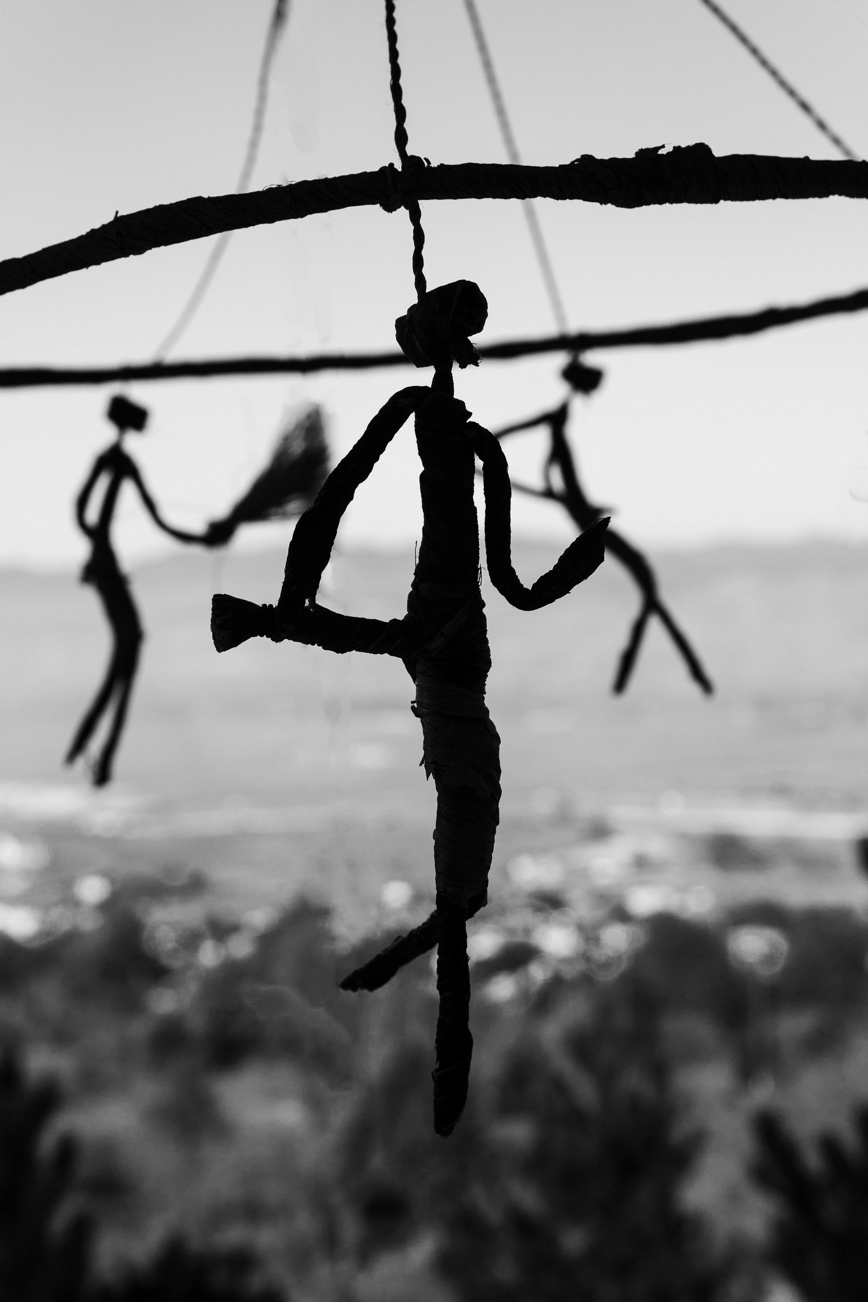 dark wrought-iron suspended roundabout with slim wrought-iron figures also suspended.