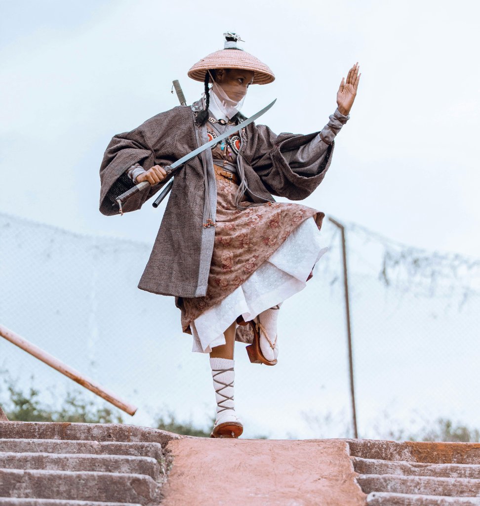 Ninja warrior in traditional clothing in lighter colors, standing on one leg, on a rooftop