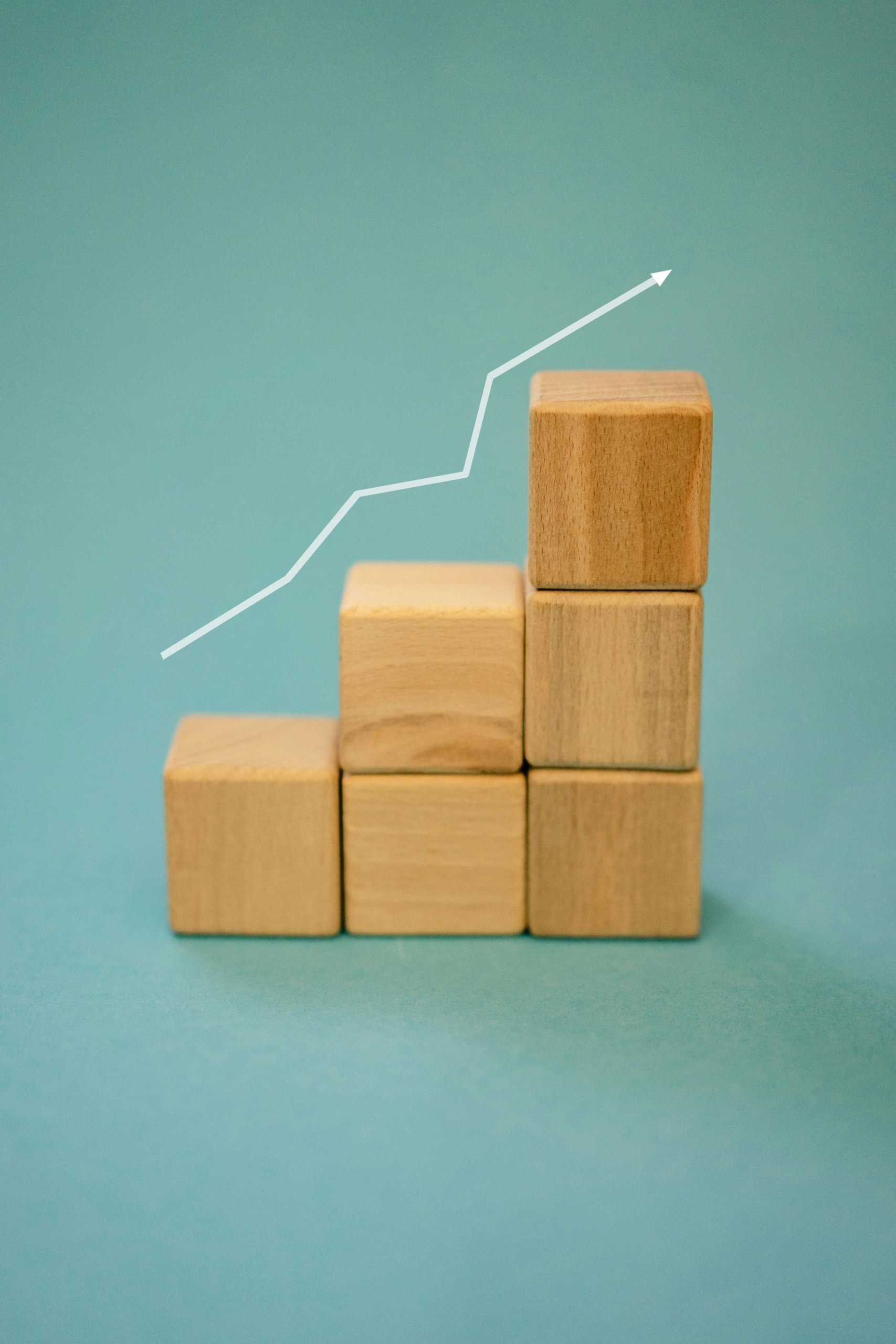 Progress chart shown in child's wood building blocks, with a white upward arrow running along the top on a turquoise background.