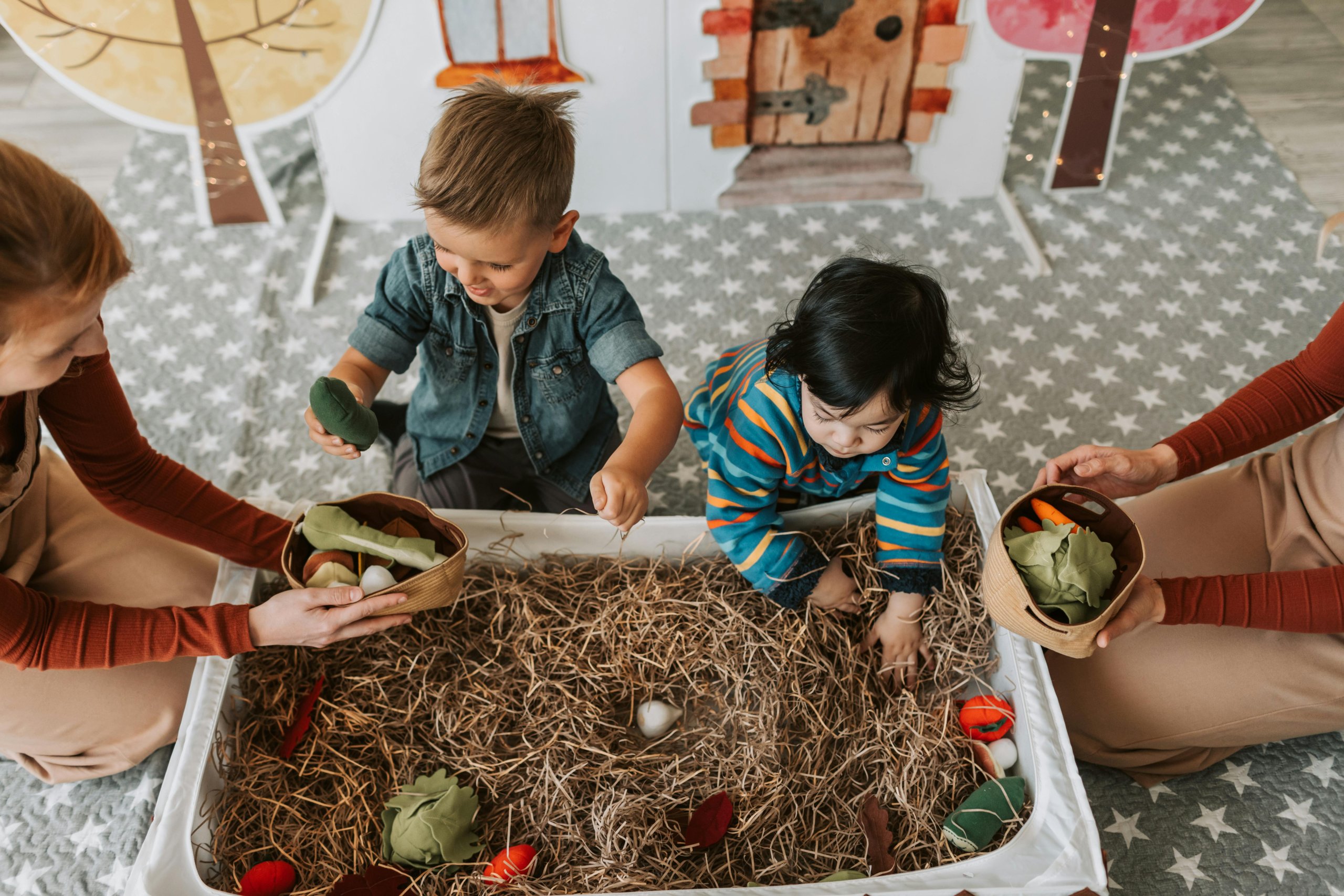 Playing in a desktop sandbox filled with straw and large toy eggs