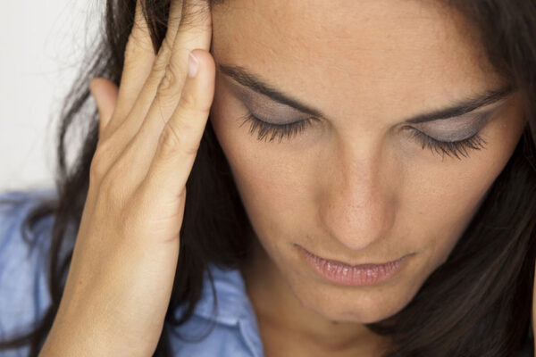 an anxious woman is holding her head in her hands looking down in despair