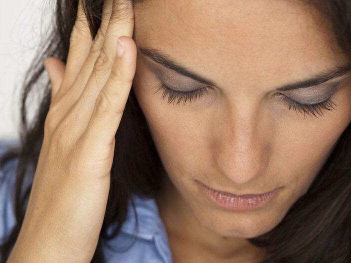 an anxious woman is holding her head in her hands looking down in despair